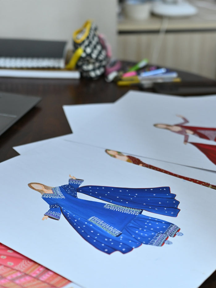Lehenga illustrations laid out across the design desk