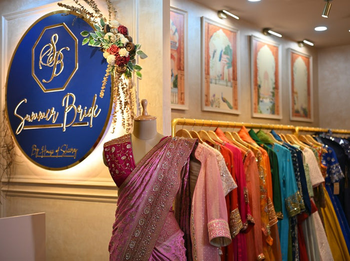 The Summer Bride sign beside a draped saree and a rail of eveningwear