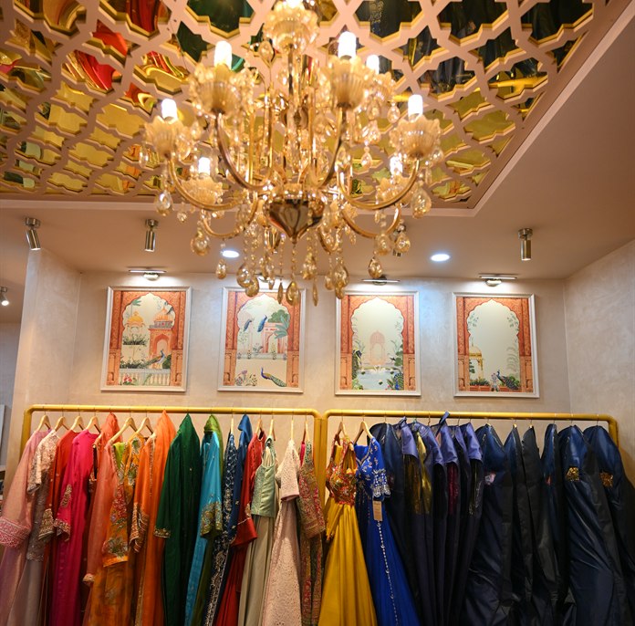 A chandelier and mirrored gold ceiling above rails of colour