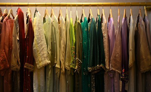 A rail of outfits in muted sage, mint and lilac